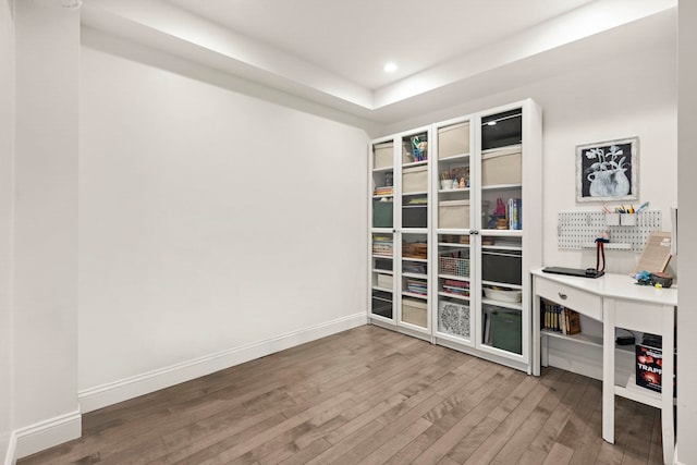 office with wood-type flooring and a tray ceiling