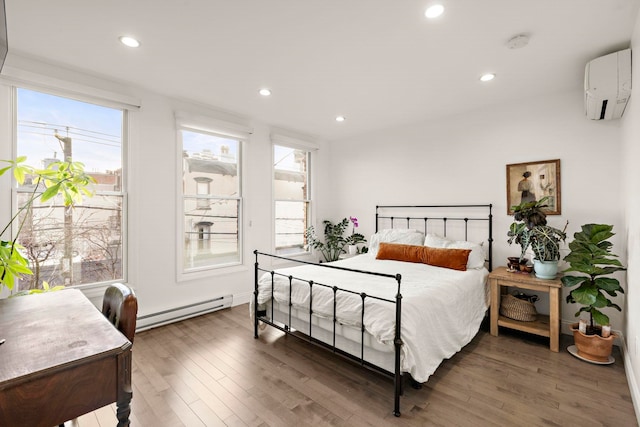 bedroom featuring a baseboard heating unit, a wall mounted AC, and dark hardwood / wood-style floors