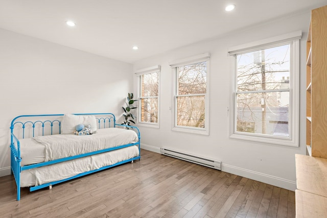 bedroom with baseboard heating, multiple windows, and hardwood / wood-style flooring