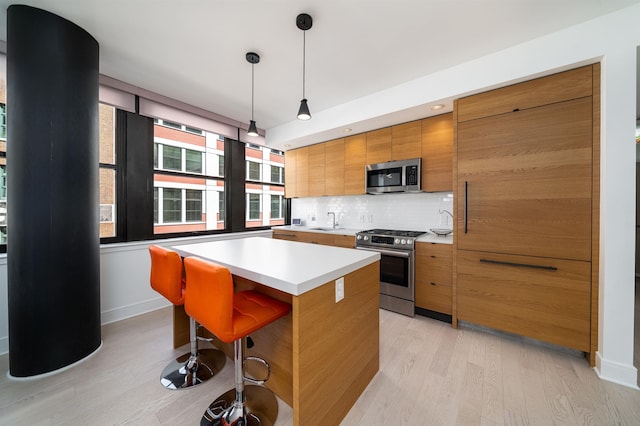 10 Provost St Unit 416, Jersey City, NJ 07302 - kitchen featuring stainless steel appliances, light wood-type flooring, brown cabinets, and decorative backsplash
