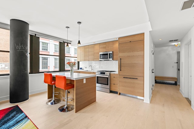 10 Provost St Unit 416, Jersey City, NJ 07302 - kitchen featuring appliances with stainless steel finishes, light wood-style floors, a center island, backsplash, and light countertops