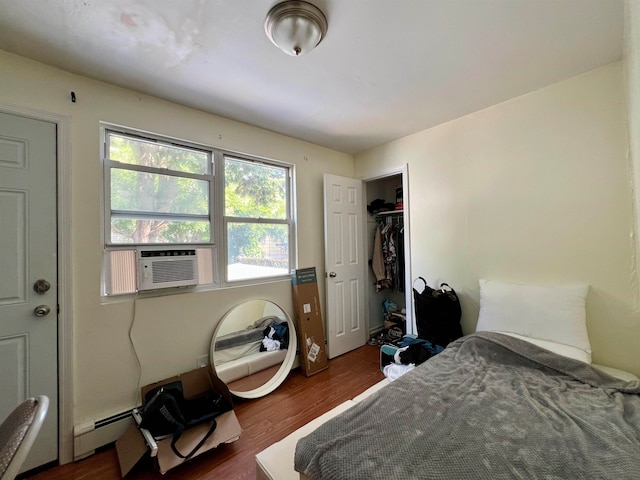 bedroom with baseboard heating, dark wood-type flooring, cooling unit, and a closet