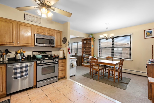 kitchen featuring dark countertops, light colored carpet, ceiling fan with notable chandelier, light tile patterned flooring, and stainless steel appliances