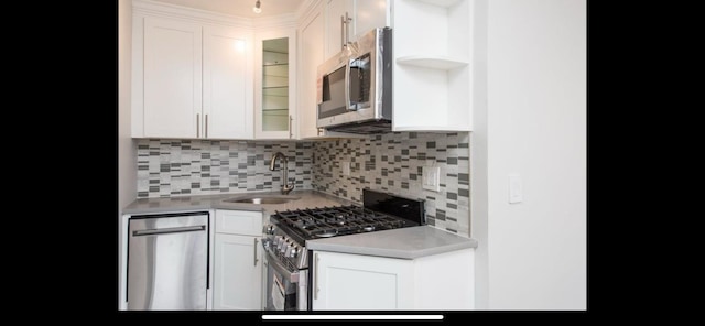 kitchen with stainless steel appliances, white cabinetry, a sink, and tasteful backsplash
