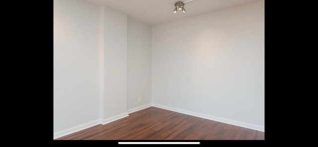empty room with baseboards and dark wood finished floors