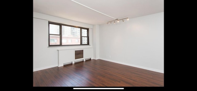 unfurnished room featuring track lighting, baseboards, and wood finished floors