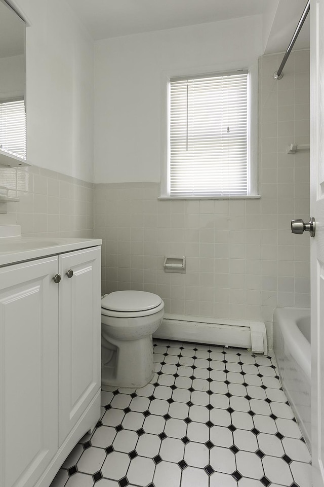 226 57th St, West New York, NJ 07093 - bathroom with a baseboard radiator, vanity, tile walls, wainscoting, and tile patterned floors