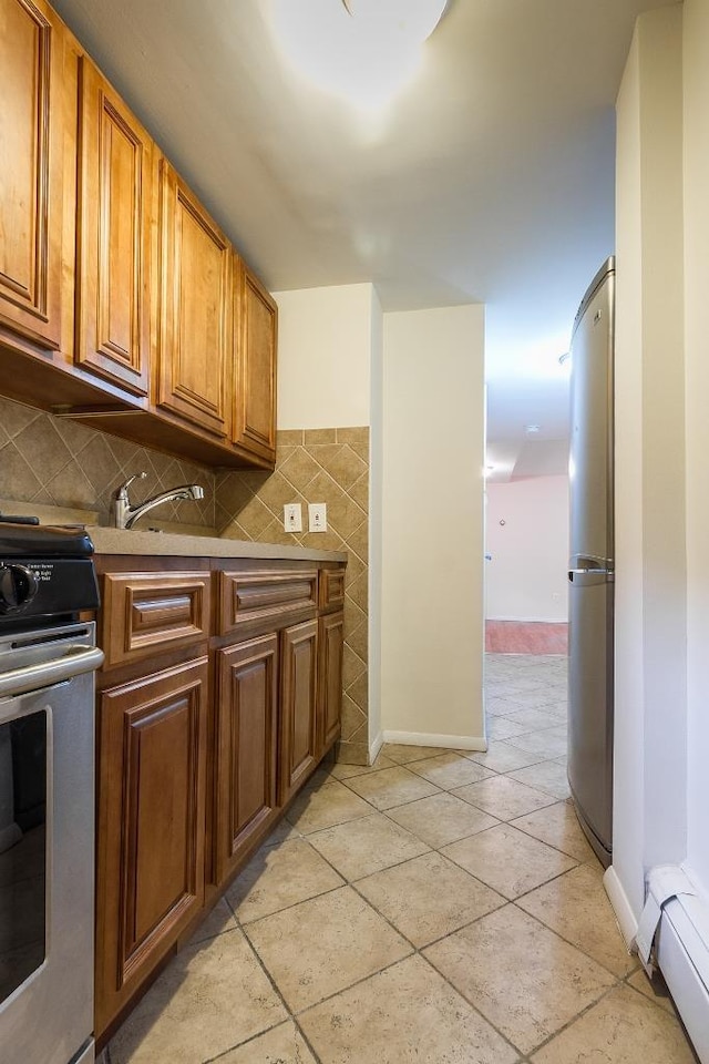226 57th St, West New York, NJ 07093 - kitchen featuring range, freestanding refrigerator, brown cabinets, a baseboard radiator, and backsplash