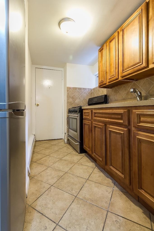 226 57th St, West New York, NJ 07093 - kitchen featuring stainless steel appliances, brown cabinetry, tasteful backsplash, and baseboard heating