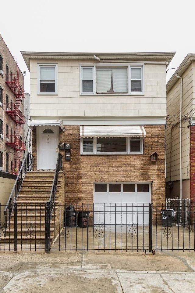 226 57th St, West New York, NJ 07093 - view of front facade with an attached garage, a fenced front yard, and concrete driveway