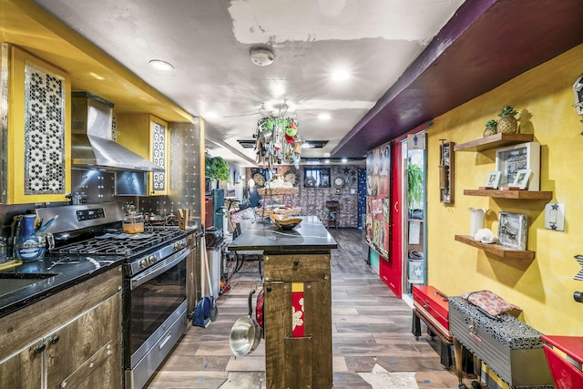 209 48th St Unit A, Union City, NJ 07087 - kitchen featuring stainless steel gas stove, wall chimney exhaust hood, dark countertops, wood finished floors, and a kitchen island