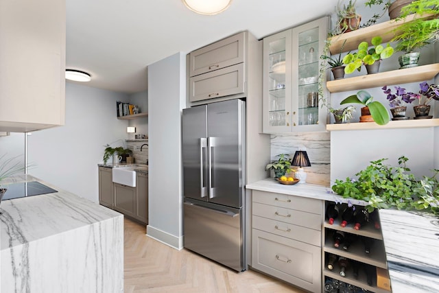 kitchen with high end fridge, sink, black electric cooktop, gray cabinets, and light parquet floors