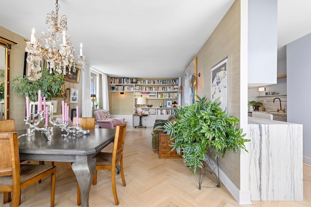 dining space with a notable chandelier, sink, and light parquet flooring