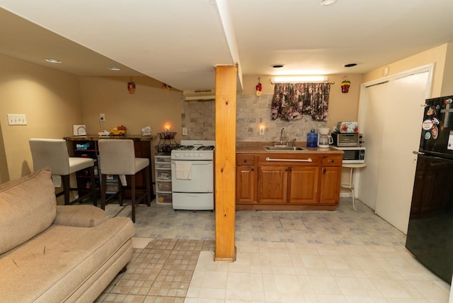 704 90th St, North Bergen, NJ 07047 - kitchen with white gas stove, freestanding refrigerator, stainless steel microwave, a sink, and decorative backsplash