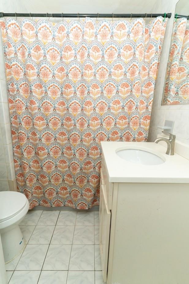 704 90th St, North Bergen, NJ 07047 - bathroom featuring vanity, toilet, tile walls, and a shower with shower curtain