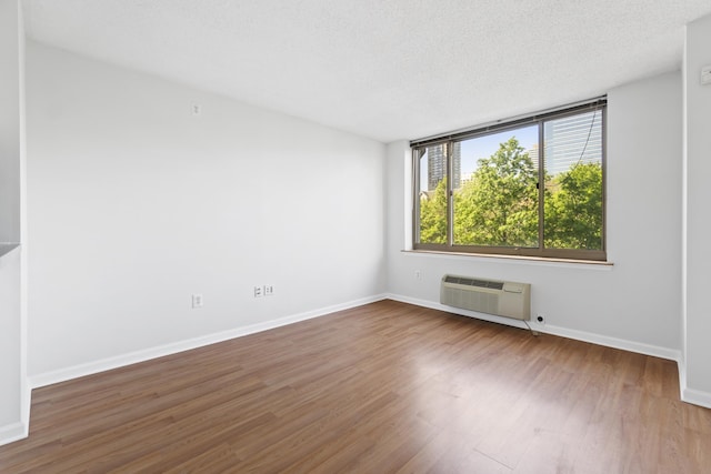 1 2nd St Unit 314, Jersey City, NJ 07302 - spare room featuring wood finished floors, baseboards, a wall unit AC, and a textured ceiling