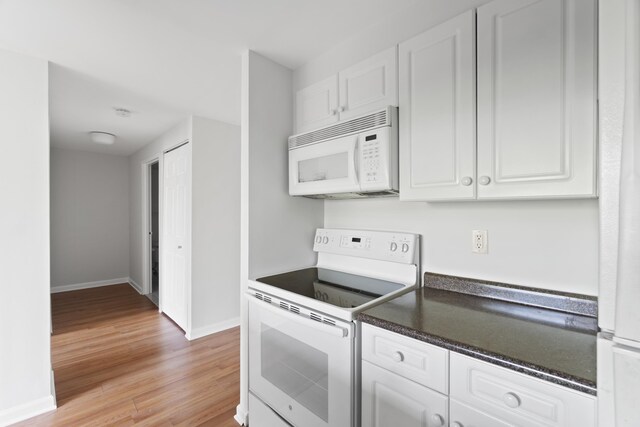 1 2nd St Unit 314, Jersey City, NJ 07302 - kitchen featuring white appliances, baseboards, white cabinets, and dark countertops