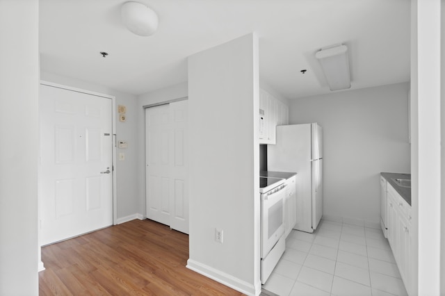 1 2nd St Unit 314, Jersey City, NJ 07302 - kitchen featuring white appliances, white cabinets, baseboards, light wood-style flooring, and dark countertops