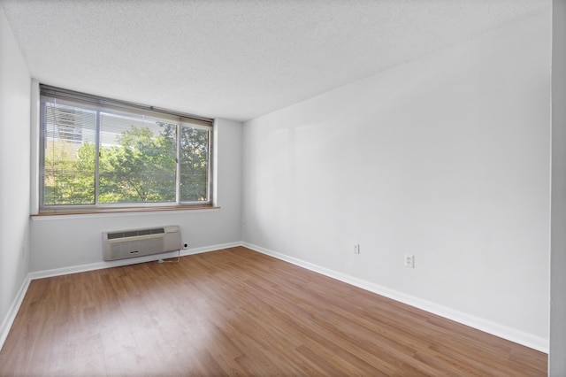 1 2nd St Unit 314, Jersey City, NJ 07302 - empty room with a wall mounted air conditioner, wood finished floors, a textured ceiling, and baseboards