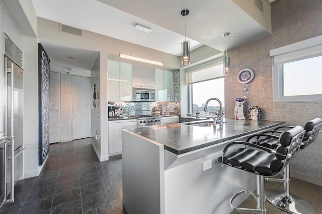 225 River St Unit 1901, Hoboken, NJ 07030 - kitchen featuring stainless steel microwave, a peninsula, a breakfast bar area, white cabinets, and dark countertops