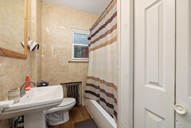 bathroom featuring radiator, toilet, wood finished floors, and shower / tub combo