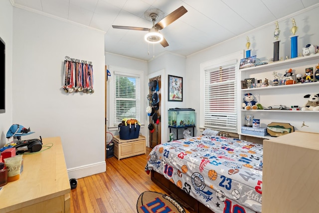 bedroom with ornamental molding, light wood-style floors, baseboards, and ceiling fan