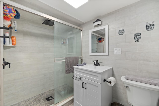 bathroom featuring a stall shower, toilet, tile walls, and vanity