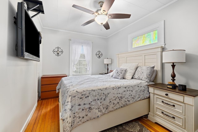 bedroom featuring ornamental molding, light wood-style flooring, baseboards, and a ceiling fan