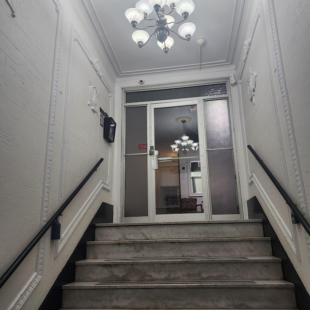 stairs featuring a chandelier and crown molding