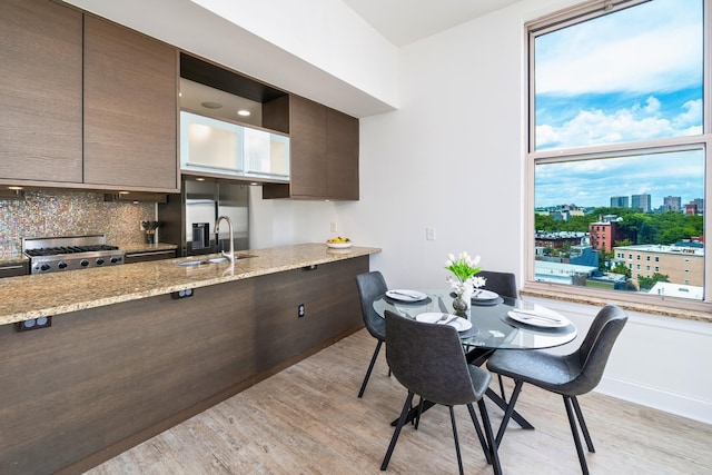 10 Regent St Unit 807, Jersey City, NJ 07302 - kitchen featuring light wood-style floors, backsplash, light stone counters, range, and dark brown cabinetry