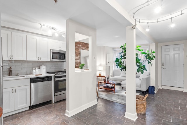 98 Bright St Unit 1G, Jersey City, NJ 07302 - kitchen with stainless steel appliances, rail lighting, baseboards, and white cabinets