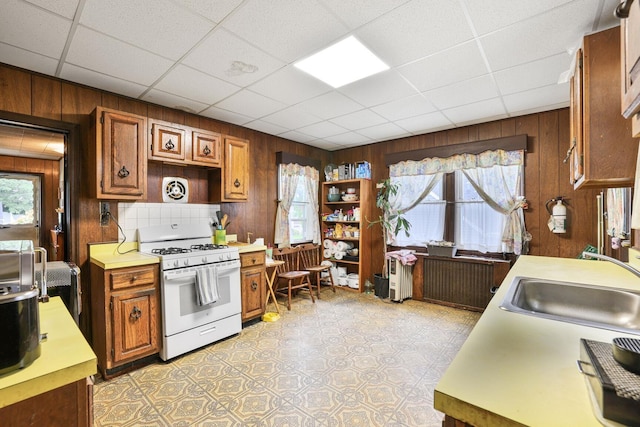 47 Darling Ave, Bloomfield, NJ 07003 - kitchen with white gas range oven, wooden walls, light countertops, brown cabinetry, and plenty of natural light