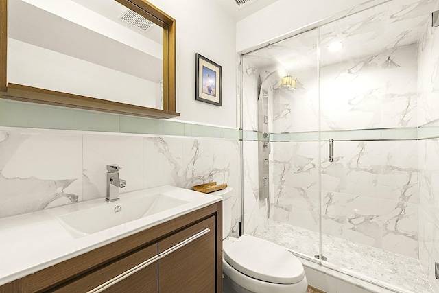 bathroom featuring walk in shower, vanity, toilet, and tile walls