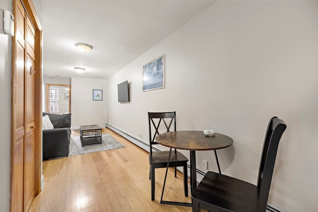 dining area with light wood-type flooring and a baseboard radiator