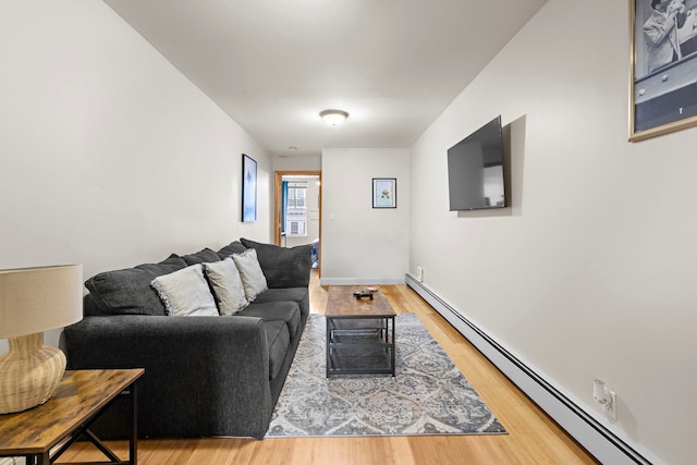 living room featuring a baseboard heating unit, wood finished floors, and baseboards