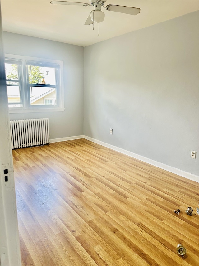 unfurnished room featuring radiator, light hardwood / wood-style flooring, and ceiling fan