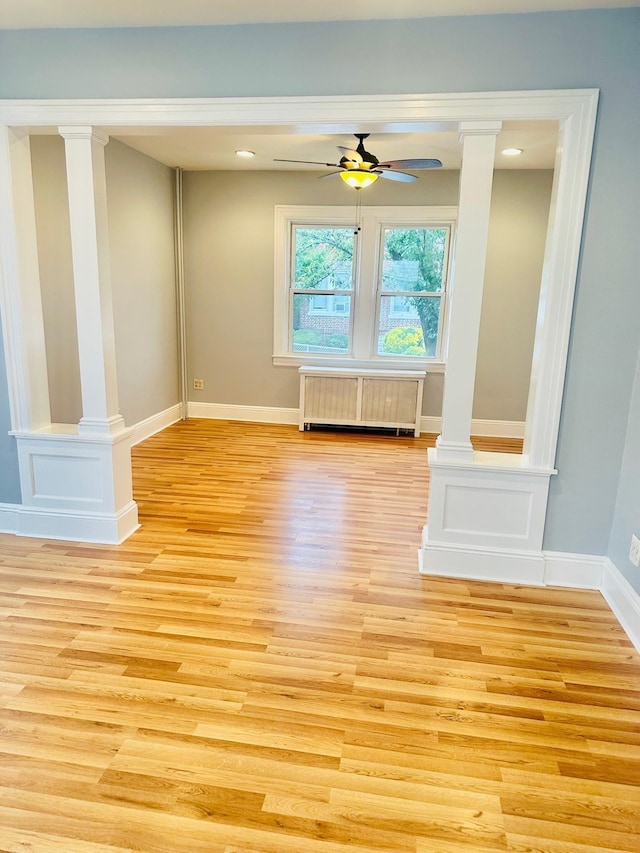 spare room with ornate columns, ceiling fan, radiator heating unit, and light hardwood / wood-style floors