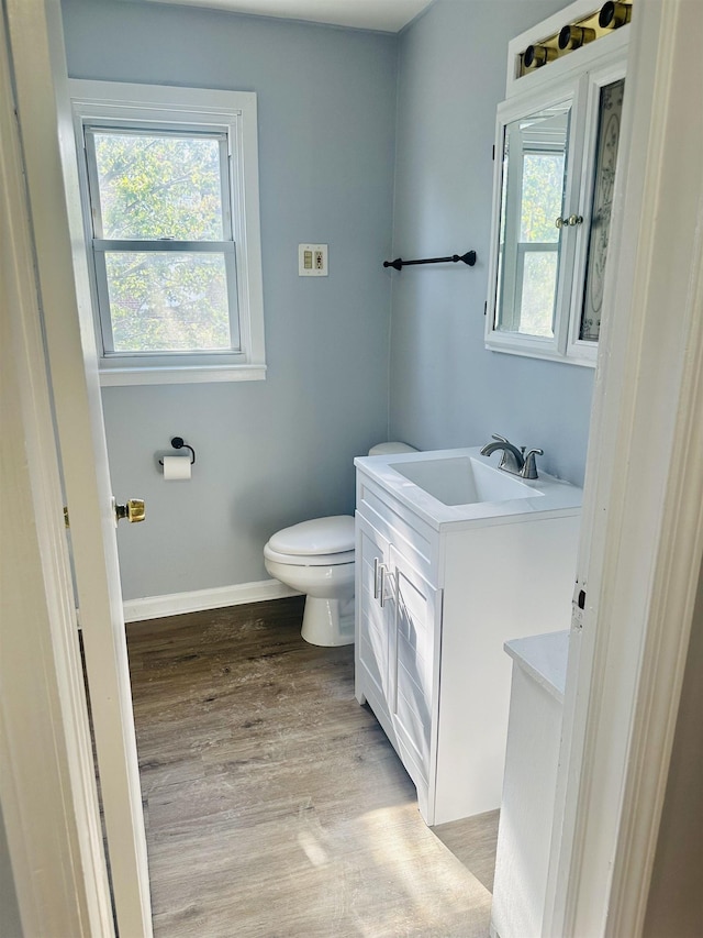 bathroom featuring vanity, a healthy amount of sunlight, hardwood / wood-style flooring, and toilet