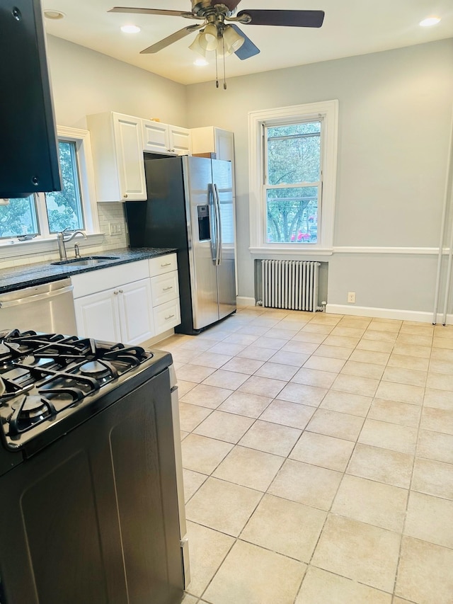 kitchen with stainless steel appliances, light tile patterned flooring, radiator, and sink