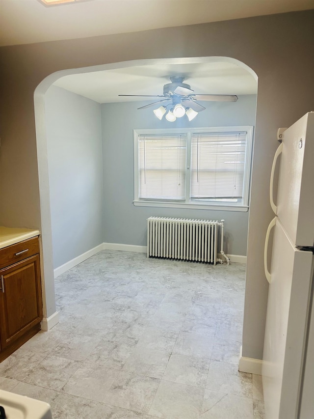 unfurnished dining area with ceiling fan, radiator, and a wealth of natural light