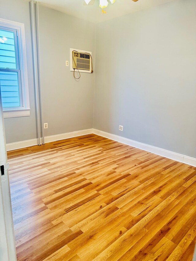 spare room featuring ceiling fan, light wood-type flooring, and an AC wall unit