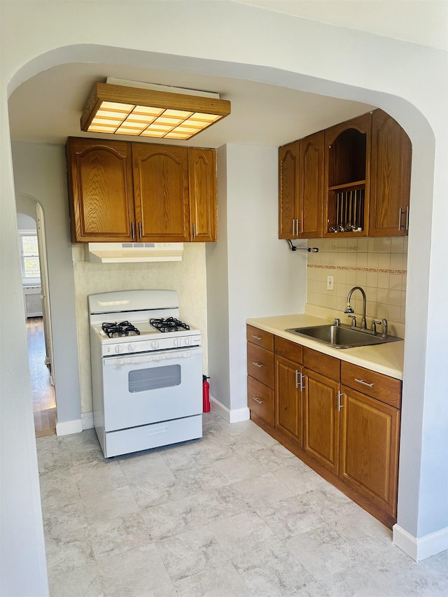 kitchen featuring tasteful backsplash, sink, and white range with gas stovetop