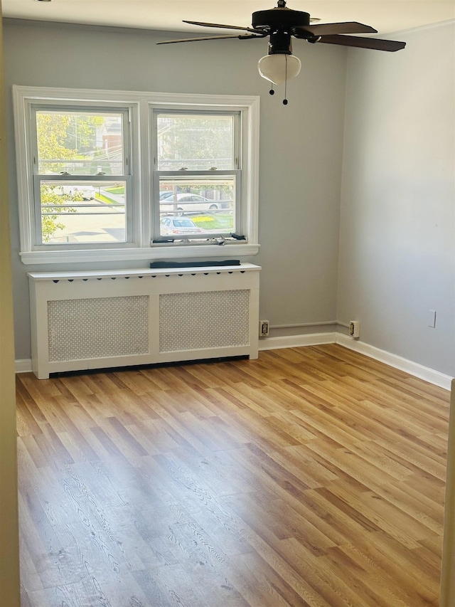 unfurnished room featuring radiator, ceiling fan, and light hardwood / wood-style flooring