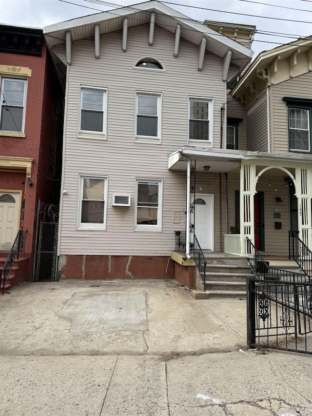 italianate-style house featuring fence and a wall unit AC