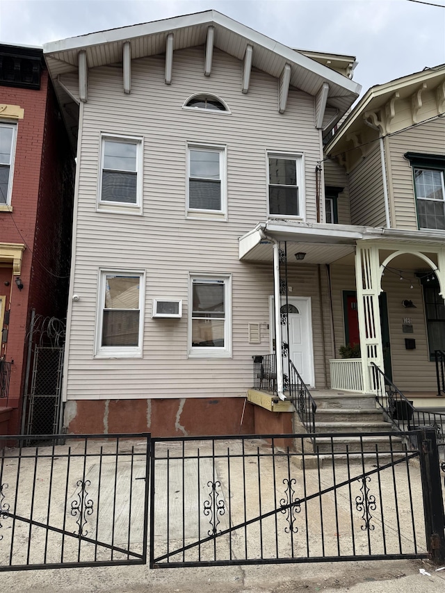 italianate home featuring a wall unit AC and fence