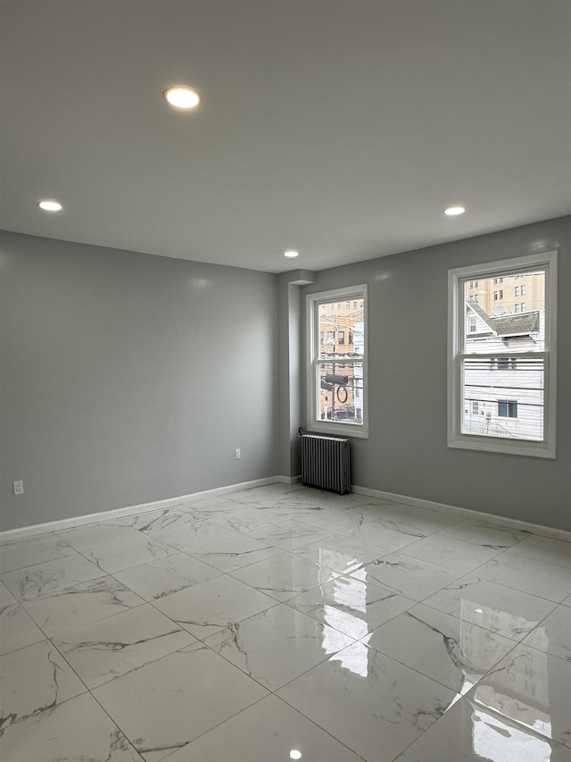 empty room featuring radiator heating unit, recessed lighting, baseboards, and marble finish floor