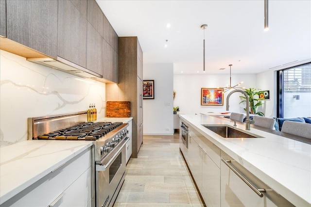 277 2nd St Unit 1, Jersey City, NJ 07302 - kitchen featuring high end stainless steel range oven, a sink, modern cabinets, light stone countertops, and a chandelier