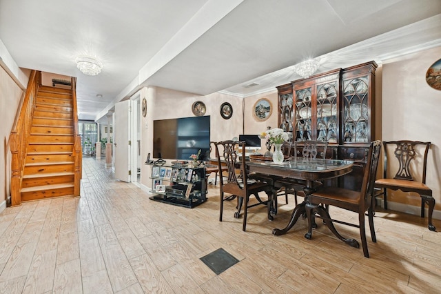 dining room featuring ornamental molding, an inviting chandelier, and light hardwood / wood-style floors