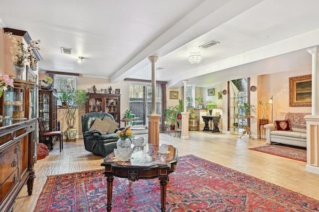 living room featuring a wealth of natural light, decorative columns, and light wood-type flooring