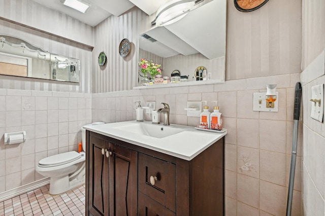 bathroom featuring tile patterned floors, vanity, toilet, and tile walls